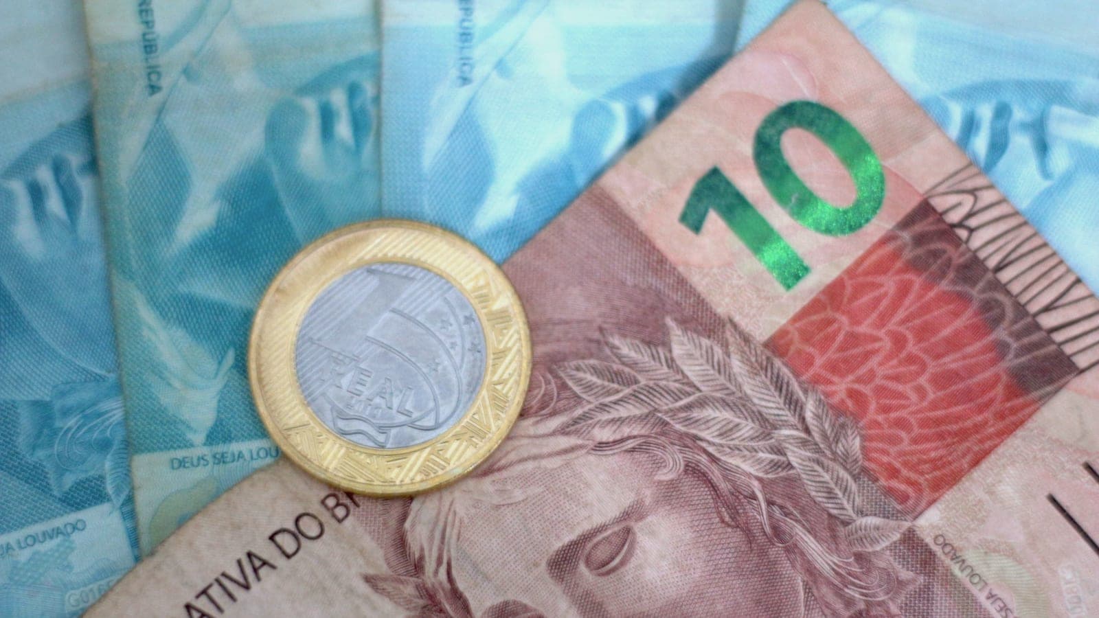 Nota de dez reais com uma moeda de um real em cima